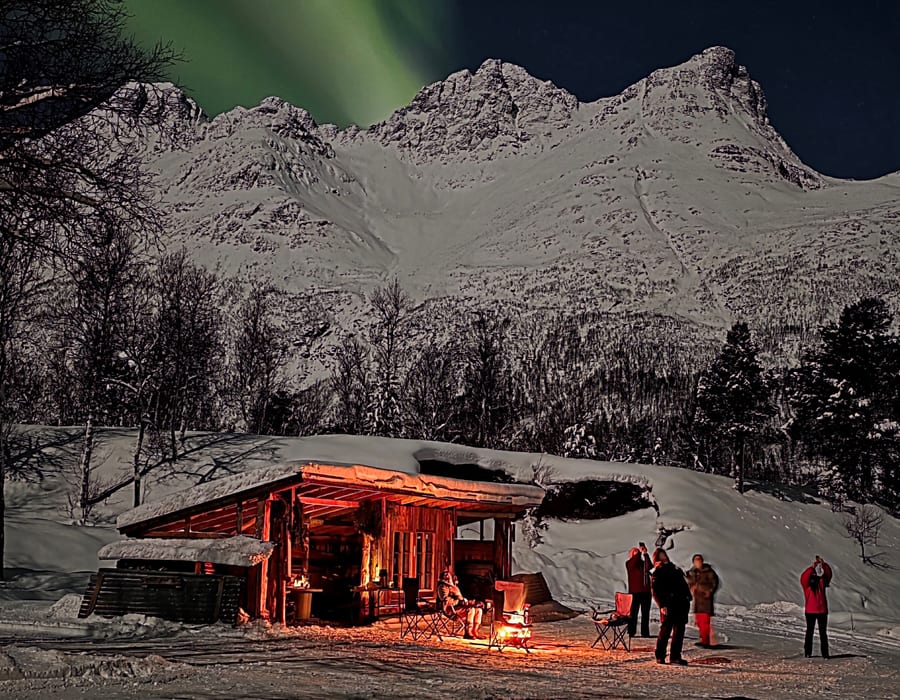 Guests around the campfire at the basecamp, mountains behind